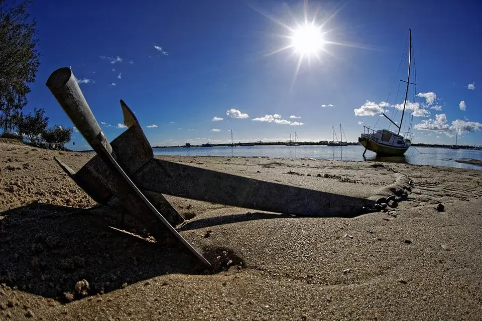 Voilier au mouillage près d’une plage avec la ligne d’ancre visible au premier plan